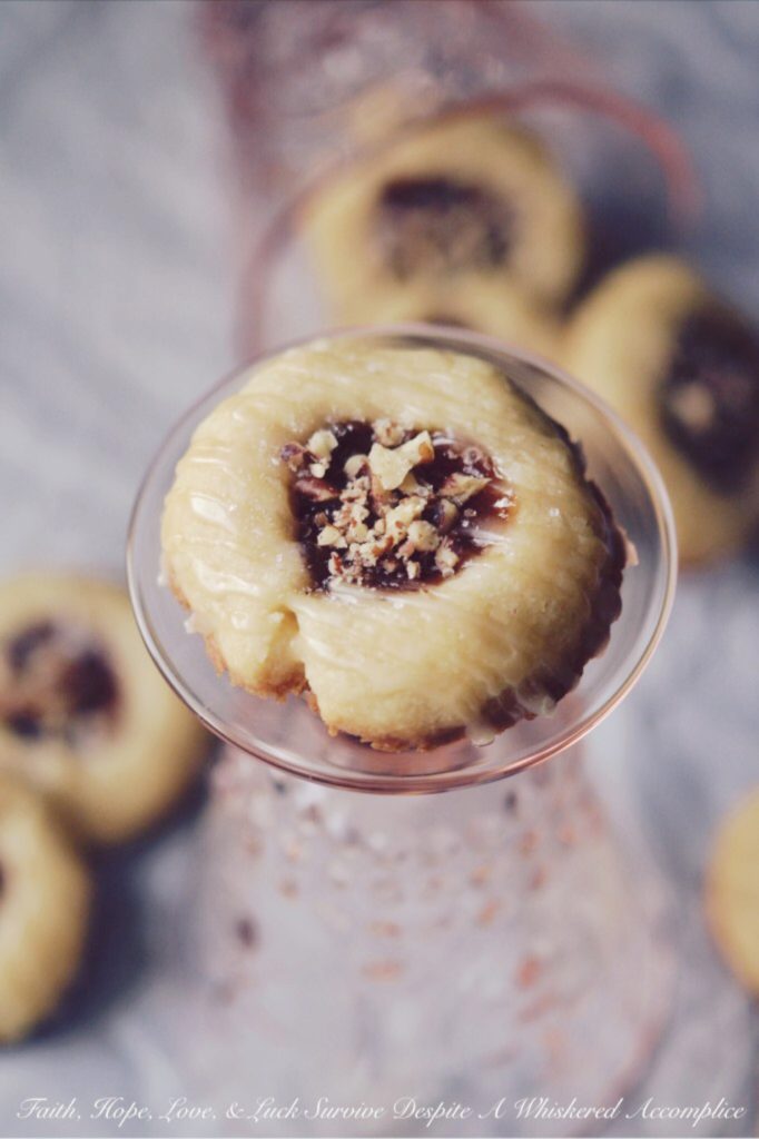 Strawberry Pecan Tea Cookies - These crumbly buttery thumbprint cookies go just as great with your morning coffee as they do with your afternoon tea. They're also just as tasty for dessert or a late-night snack. Filled with strawberry preserves, sprinkled with finely chopped pecans, and then drizzled with a sweet vanilla icing, these are one sweet crunchy tea cookie that you'll instantly swoon over.