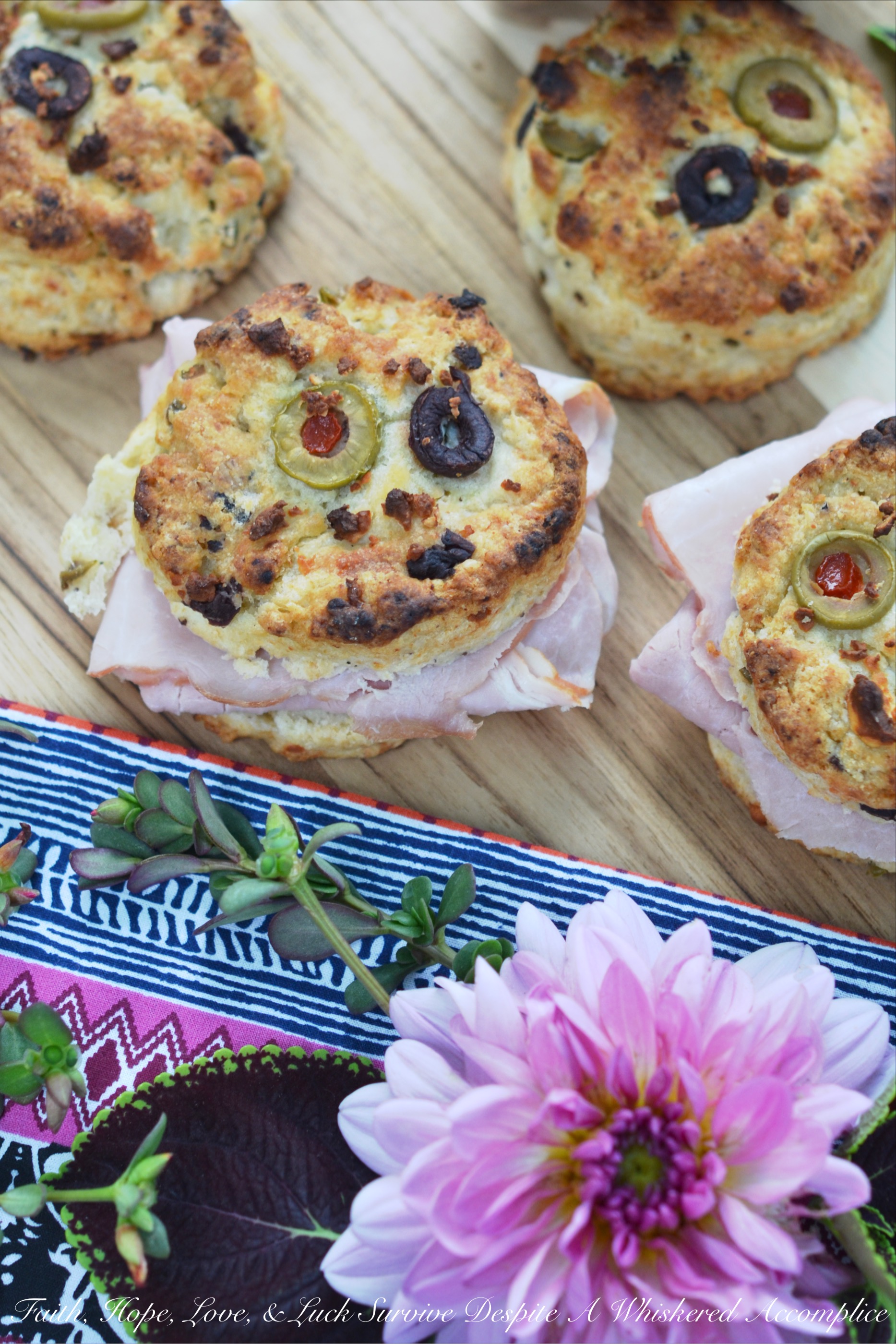 Olive & Feta Cheese Ham Biscuits - These southern ham biscuits are given a unique Mediterranean twist with the addition of olives and feta cheese. Whether you eat them for breakfast, lunch, or dinner, you're sure to enjoy these flavorful crumbly and buttery biscuit sandwiches.