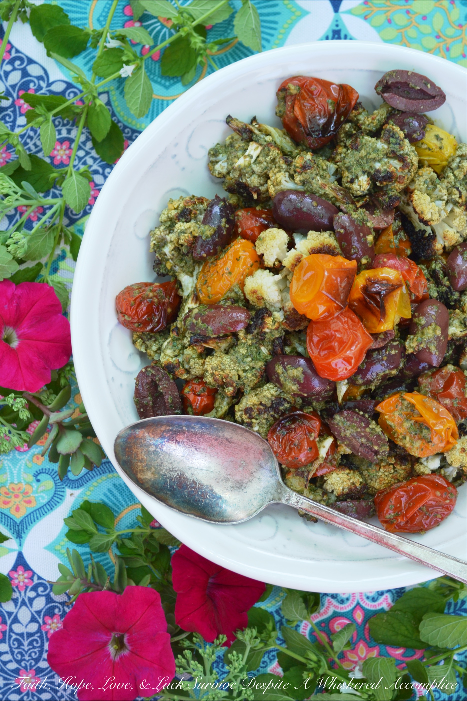 Oven-Roasted Cauliflower & Tomato Salad - Oven-roasted cauliflower and cherry tomatoes are transformed into a Mediterranean summer side salad, by adding homemade basil pesto sauce and kalamata olives. The basil pesto sauce is easy to make by just tossing fresh basil, pumpkin seeds or pepitas, olive oil, red wine vinegar, salt, and pepper into a food processor. This is a simple recipe that really bumps up the flavor of fresh summer produce.