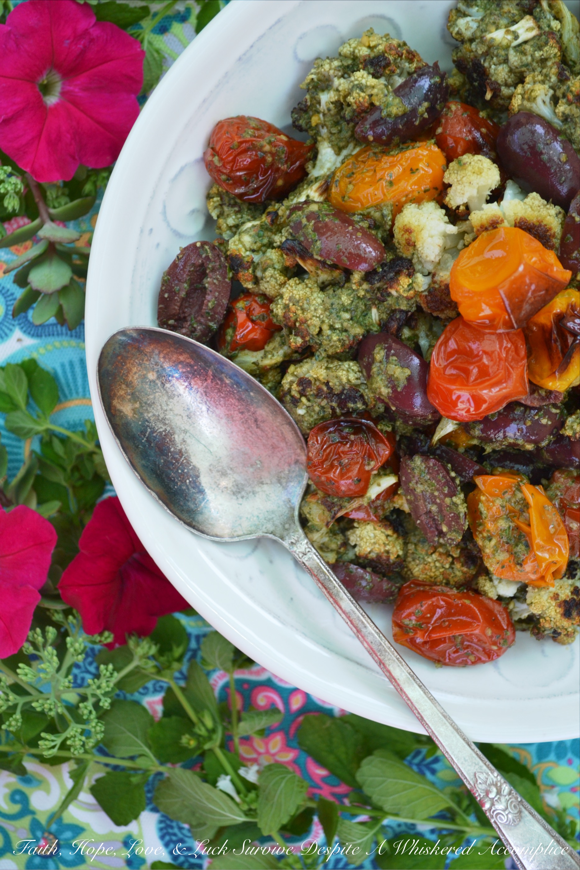 Oven-Roasted Cauliflower & Tomato Salad - Oven-roasted cauliflower and cherry tomatoes are transformed into a Mediterranean summer side salad, by adding homemade basil pesto sauce and kalamata olives. The basil pesto sauce is easy to make by just tossing fresh basil, pumpkin seeds or pepitas, olive oil, red wine vinegar, salt, and pepper into a food processor. This is a simple recipe that really bumps up the flavor of fresh summer produce.