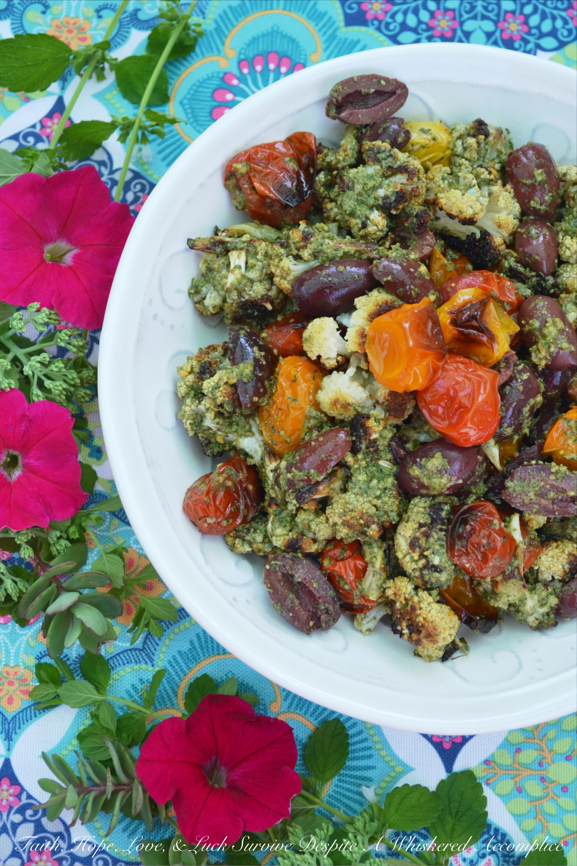 Oven-Roasted Cauliflower & Tomato Salad - Oven-roasted cauliflower and cherry tomatoes are transformed into a Mediterranean summer side salad, by adding homemade basil pesto sauce and kalamata olives. The basil pesto sauce is easy to make by just tossing fresh basil, pumpkin seeds or pepitas, olive oil, red wine vinegar, salt, and pepper into a food processor. This is a simple recipe that really bumps up the flavor of fresh summer produce.