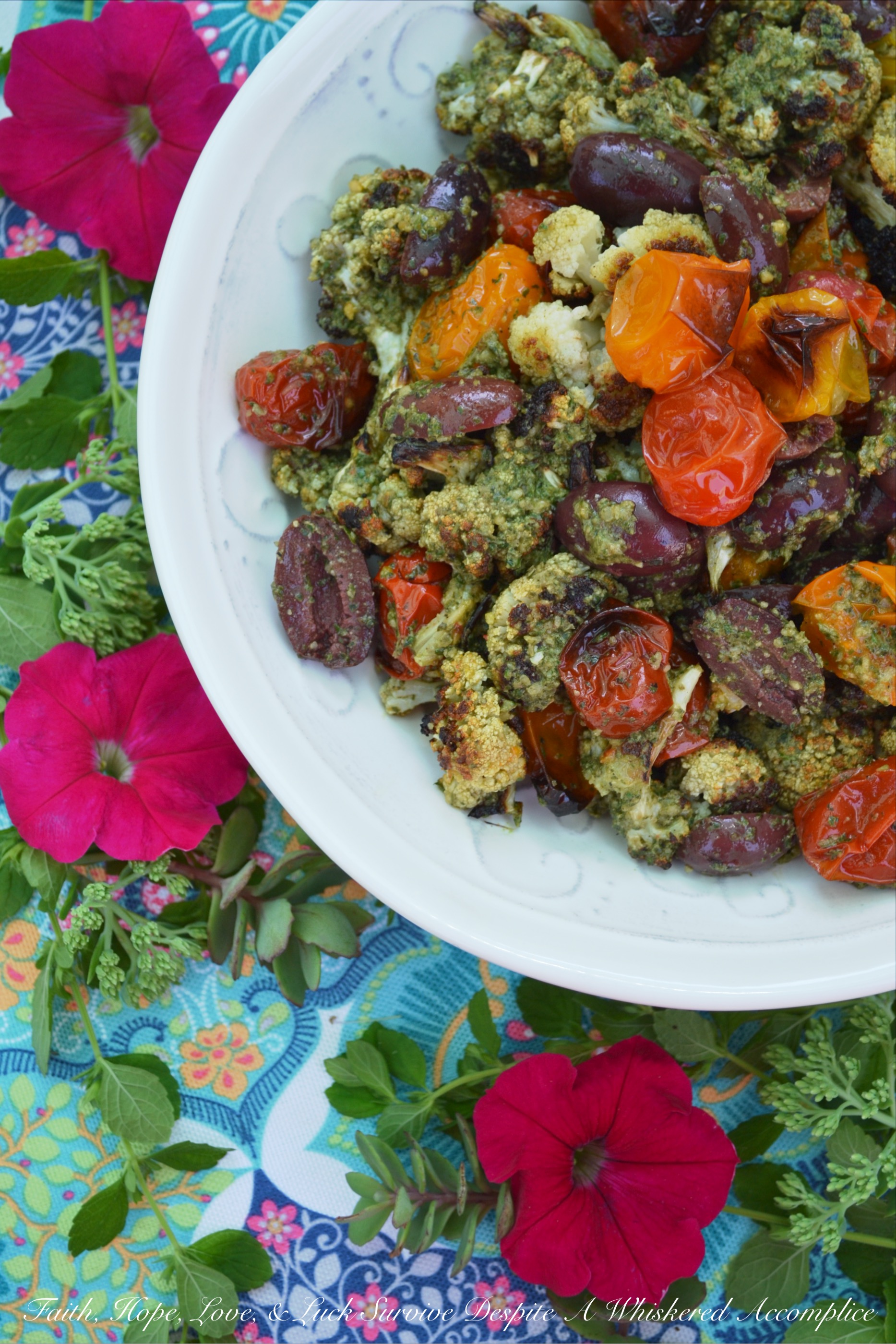 Oven-Roasted Cauliflower & Tomato Salad - Oven-roasted cauliflower and cherry tomatoes are transformed into a Mediterranean summer side salad, by adding homemade basil pesto sauce and kalamata olives. The basil pesto sauce is easy to make by just tossing fresh basil, pumpkin seeds or pepitas, olive oil, red wine vinegar, salt, and pepper into a food processor. This is a simple recipe that really bumps up the flavor of fresh summer produce.