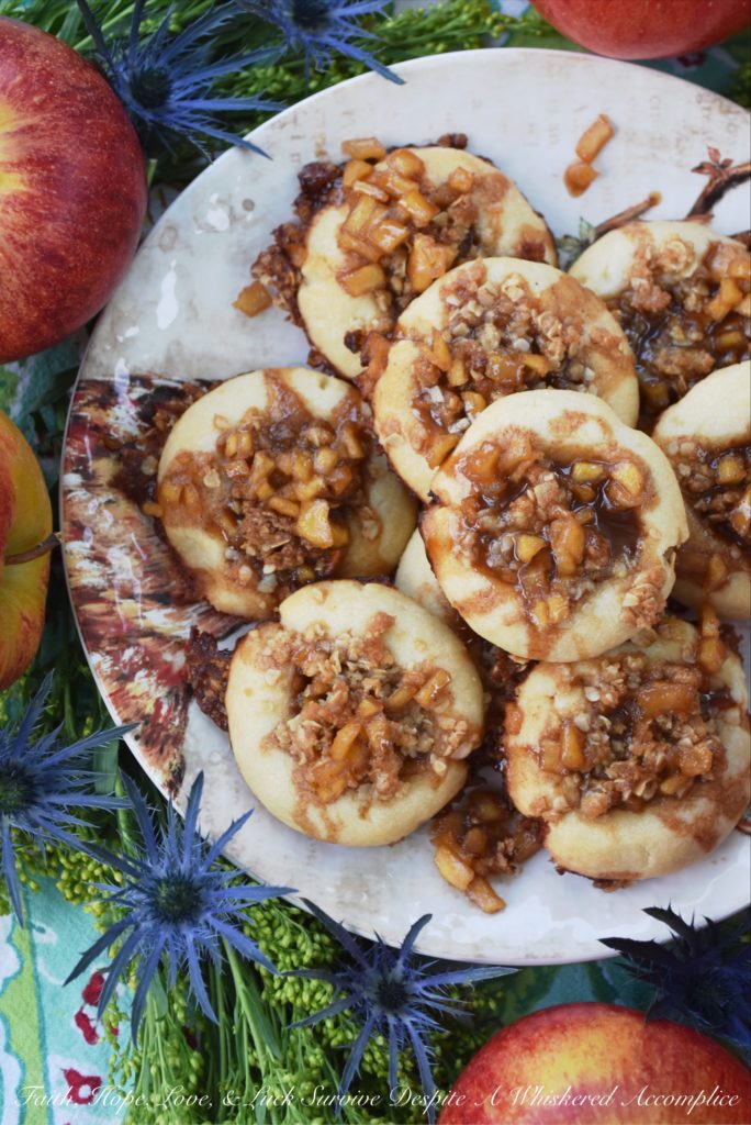Buttery Apple Streusel Thumbprint Cookies - What's better than a cookie? A buttery cookie, filled with cinnamon caramel apple sauce, topped with sweet oatmeal streusel topping, and then drizzled with more cinnamon caramel apple sauce. Are you drooling yet? I know I am. Really, this is simply one thumbprint cookie you just have to make this fall.