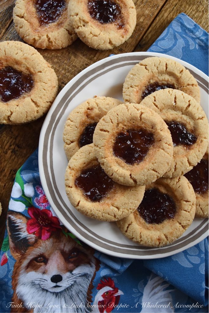 Peanut Butter Sugar Cookies with Plum Preserves - When you're in the mood to fancy things up a bit, but you're still craving peanut butter and jelly, these cookies are just the thing. Each peanut butter flavored ball of dough is rolled in granulated sugar and then filled with a small spoonful of plum preserves. These peanut butter sugar cookies are crunchy, chewy, gooey, and sweet all at the same time, making them the perfect cookie, no matter what the occasion.