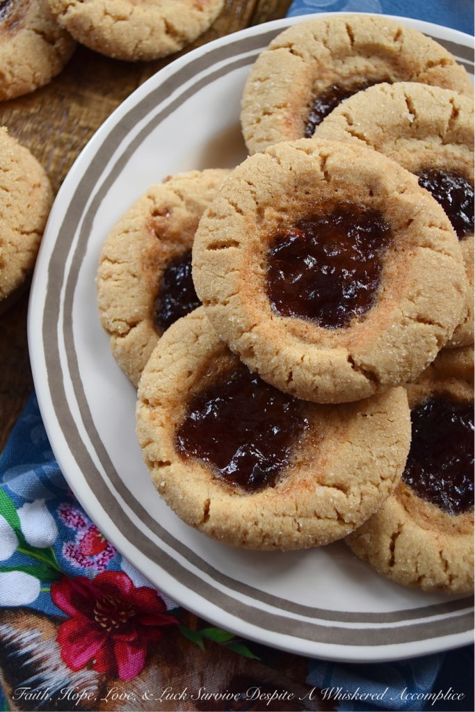 Peanut Butter Sugar Cookies with Plum Preserves - When you're in the mood to fancy things up a bit, but you're still craving peanut butter and jelly, these cookies are just the thing. Each peanut butter flavored ball of dough is rolled in granulated sugar and then filled with a small spoonful of plum preserves. These peanut butter sugar cookies are crunchy, chewy, gooey, and sweet all at the same time, making them the perfect cookie, no matter what the occasion.