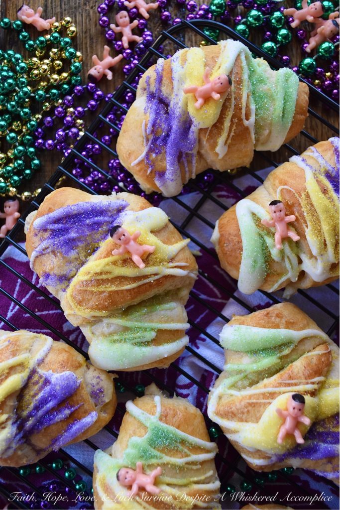 Mardi Gras Cream Cheese King Cake Croissants - Unable to find a king cake to celebrate Mardi Gras this year? With these cream cheese croissants, made using refrigerated crescent rolls, you'll be able to celebrate the holiday with very little effort involved. And, once you decorate each king cake croissant with some yellow, green, and purple sanding sugar and a small plastic Mardi Gras baby, you'll have a festive treat everyone in your family will love. Laissez les bons temps rouler.