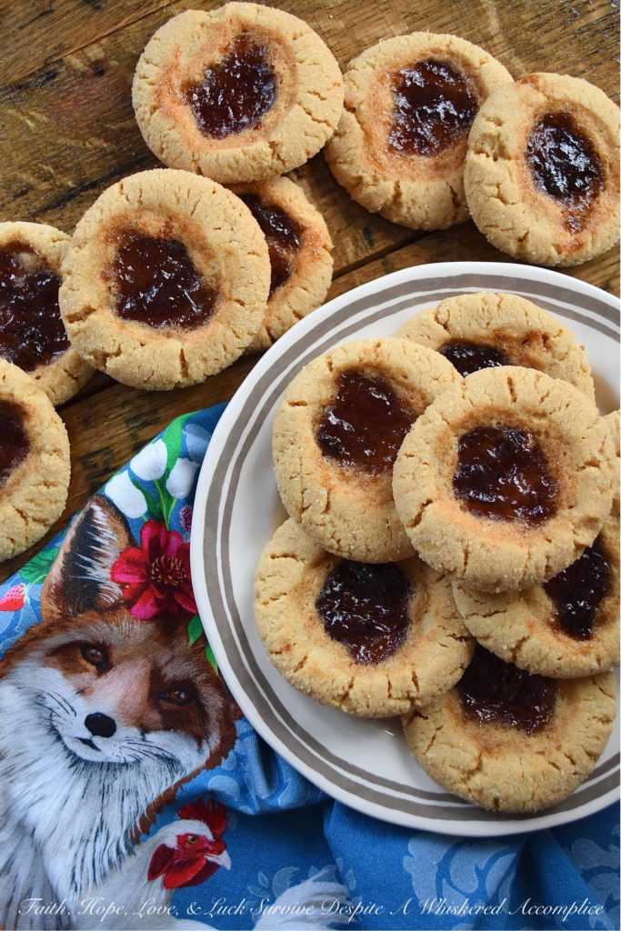 Peanut Butter Sugar Cookies with Plum Preserves - When you're in the mood to fancy things up a bit, but you're still craving peanut butter and jelly, these cookies are just the thing. Each peanut butter flavored ball of dough is rolled in granulated sugar and then filled with a small spoonful of plum preserves. These peanut butter sugar cookies are crunchy, chewy, gooey, and sweet all at the same time, making them the perfect cookie, no matter what the occasion.