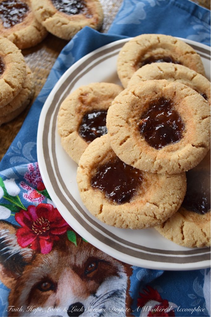 Peanut Butter Sugar Cookies with Plum Preserves - When you're in the mood to fancy things up a bit, but you're still craving peanut butter and jelly, these cookies are just the thing. Each peanut butter flavored ball of dough is rolled in granulated sugar and then filled with a small spoonful of plum preserves. These peanut butter sugar cookies are crunchy, chewy, gooey, and sweet all at the same time, making them the perfect cookie, no matter what the occasion.