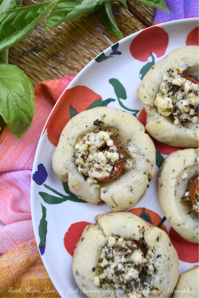 Savory Cherry Tomato, Basil, & Feta Cookies - This savory thumbprint cookie recipe is perfect for summer when fresh tomatoes and fresh basil are at their prime. The cookie dough is just a little bit sweet, while the feta cheese filling has the perfect amount of saltiness to balance out the flavor of the fresh cherry tomato it is baked on top of. Now sure, you could absolutely put this same feta and basil filling on top of baked bread all summer long, but why do that, when you can have it on top of a savory cookie instead?