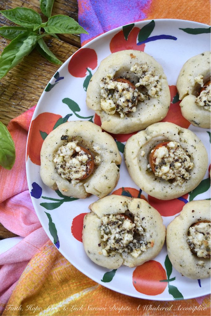 Savory Cherry Tomato, Basil, & Feta Cookies - This savory thumbprint cookie recipe is perfect for summer when fresh tomatoes and fresh basil are at their prime. The cookie dough is just a little bit sweet, while the feta cheese filling has the perfect amount of saltiness to balance out the flavor of the fresh cherry tomato it is baked on top of. Now sure, you could absolutely put this same feta and basil filling on top of baked bread all summer long, but why do that, when you can have it on top of a savory cookie instead?