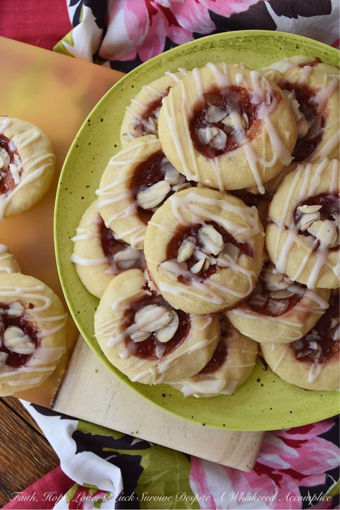 Dark Rum Cherry Almond Thumbprint Cookies - What's better than a Christmas thumbprint cookie? A boozy Christmas thumbprint cookie made using dark rum and cherry preserves. Add on a drizzle of powdered sugar rum glaze and a few sliced almonds, and these boozy Christmas cookies will certainly grab your attention with their festive presentation if not their amazing and absolutely delicious taste.