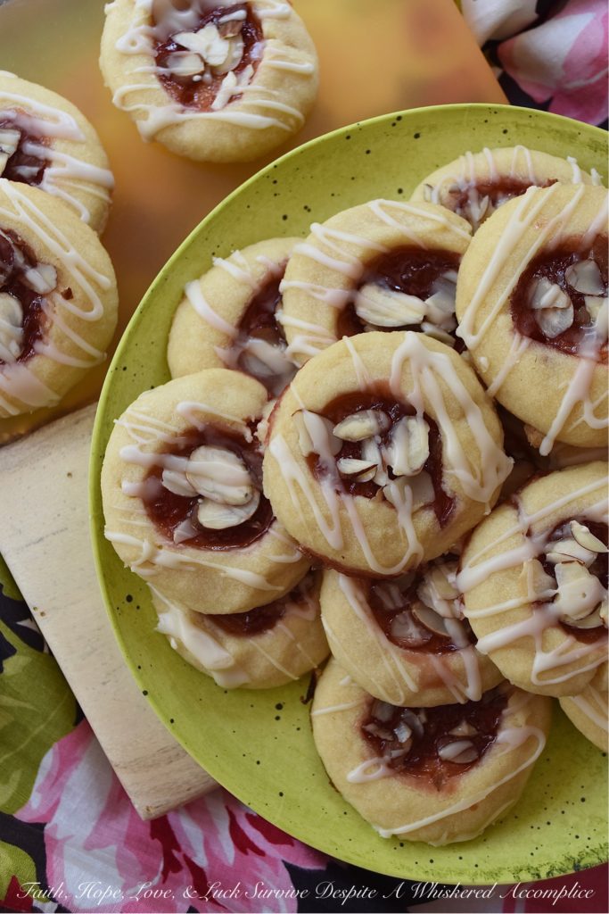 Dark Rum Cherry Almond Thumbprint Cookies - What's better than a Christmas thumbprint cookie? A boozy Christmas thumbprint cookie made using dark rum and cherry preserves. Add on a drizzle of powdered sugar rum glaze and a few sliced almonds, and these boozy Christmas cookies will certainly grab your attention with their festive presentation if not their amazing and absolutely delicious taste.