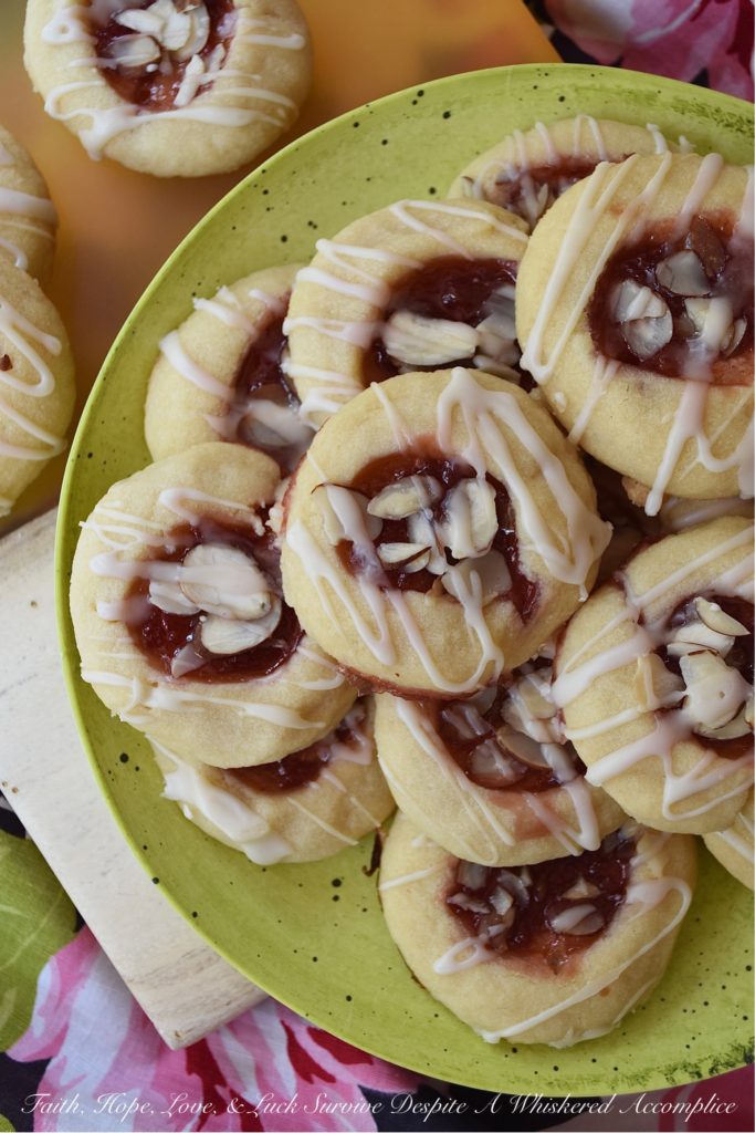 Dark Rum Cherry Almond Thumbprint Cookies - What's better than a Christmas thumbprint cookie? A boozy Christmas thumbprint cookie made using dark rum and cherry preserves. Add on a drizzle of powdered sugar rum glaze and a few sliced almonds, and these boozy Christmas cookies will certainly grab your attention with their festive presentation if not their amazing and absolutely delicious taste.