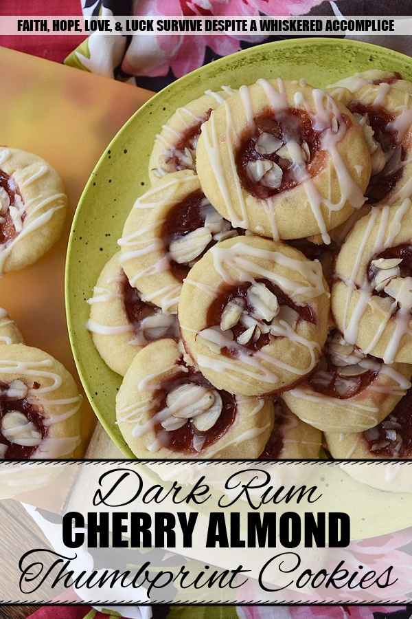 Dark Rum Cherry Almond Thumbprint Cookies - What's better than a Christmas thumbprint cookie? A boozy Christmas thumbprint cookie made using dark rum and cherry preserves. Add on a drizzle of powdered sugar rum glaze and a few sliced almonds, and these boozy Christmas cookies will certainly grab your attention with their festive presentation if not their amazing and absolutely delicious taste.