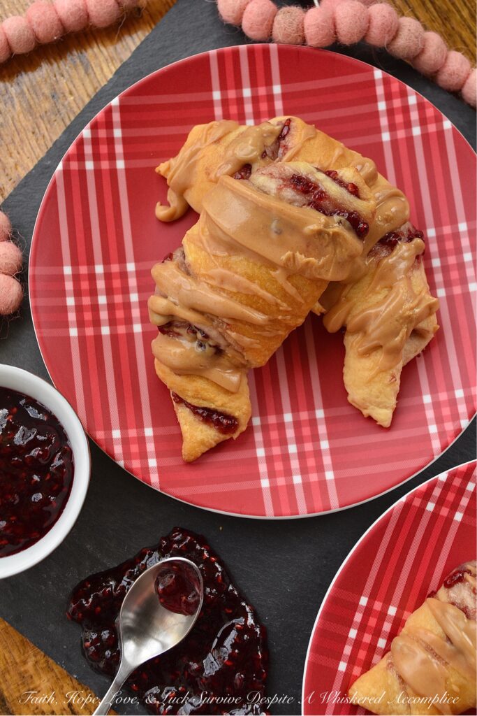 Raspberry & Peanut Butter Glazed Crescent Rolls - Are you a huge PB&J fan? Are peanut butter and jelly two of your favorite can't live without ingredients? If so, you're going to totally swoon over these raspberry and peanut butter glazed crescent rolls. I mean, how can you resist a crescent roll stuffed with raspberry preserves, jam, or jelly? Especially when it's topped with a smooth, creamy, and decadent peanut butter glaze.
