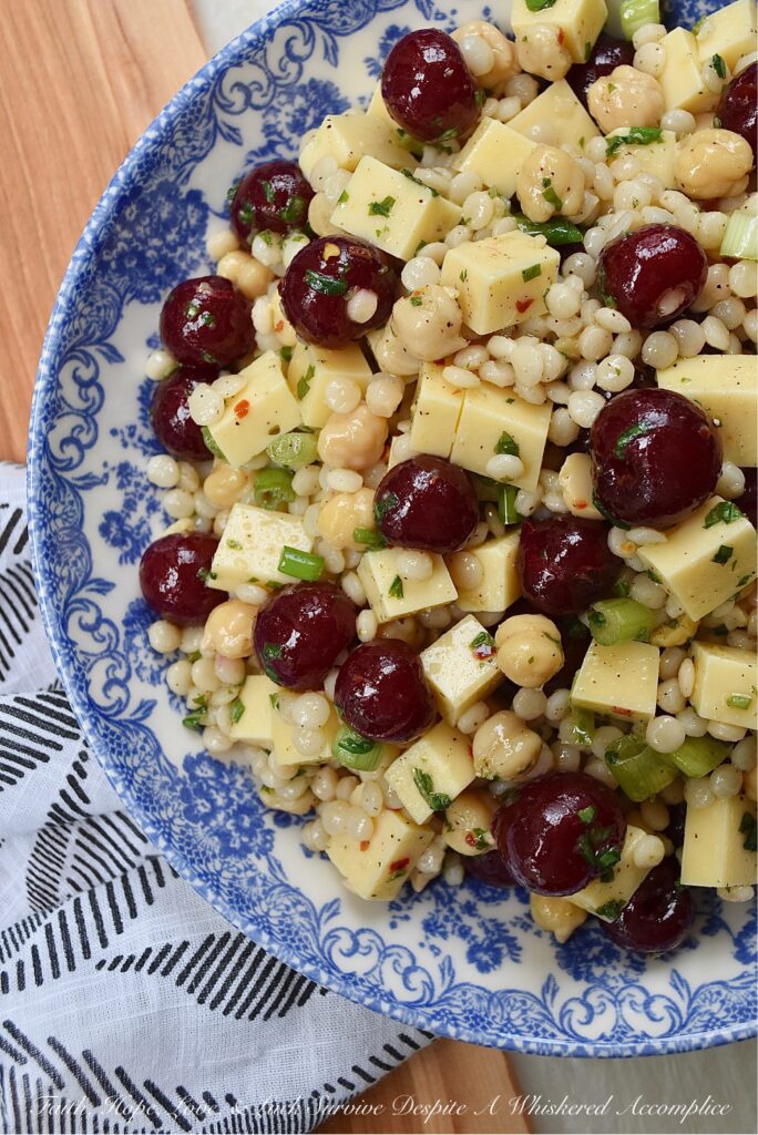 Couscous Salad with Gouda & Fresh Cherries - Ditch your traditional pasta salad recipe and switch things up for once with this colorful, fresh, and flavorful couscous salad. This unique pearl or Israeli couscous side dish uses fresh cherries, cubed gouda, canned chickpeas, and a fresh basil vinaigrette to add lots of bold and bright flavors.