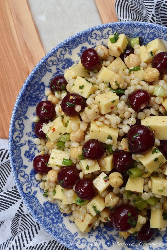 Couscous Salad with Gouda & Fresh Cherries - Ditch your traditional pasta salad recipe and switch things up for once with this colorful, fresh, and flavorful couscous salad. This unique pearl or Israeli couscous side dish uses fresh cherries, cubed gouda, canned chickpeas, and a fresh basil vinaigrette to add lots of bold and bright flavors.