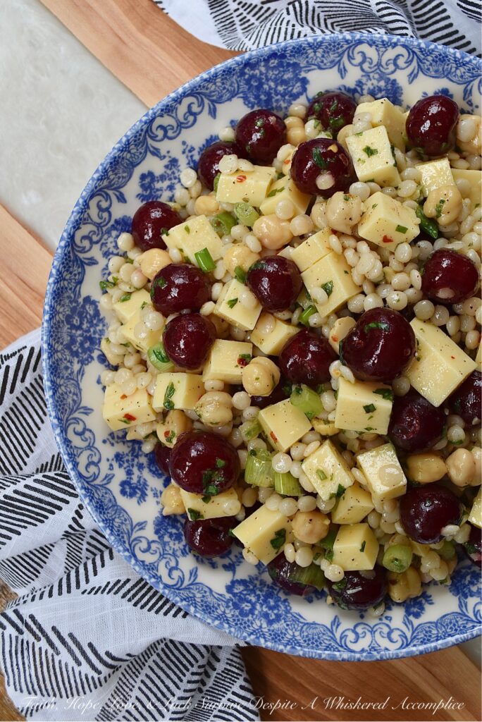 Couscous Salad with Gouda & Fresh Cherries - Ditch your traditional pasta salad recipe and switch things up for once with this colorful, fresh, and flavorful couscous salad. This unique pearl or Israeli couscous side dish uses fresh cherries, cubed gouda, canned chickpeas, and a fresh basil vinaigrette to add lots of bold and bright flavors.