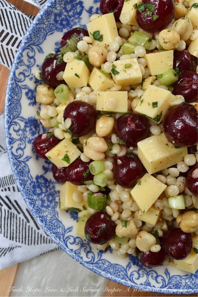 Couscous Salad with Gouda & Fresh Cherries - Ditch your traditional pasta salad recipe and switch things up for once with this colorful, fresh, and flavorful couscous salad. This unique pearl or Israeli couscous side dish uses fresh cherries, cubed gouda, canned chickpeas, and a fresh basil vinaigrette to add lots of bold and bright flavors.