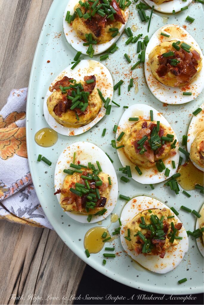 Bacon & Chive Deviled Eggs with Hot Honey - Deviled eggs are a classic crowd-pleaser and perfect for warm weather. If you're thinking about hosting a summer picnic or gathering, you definitely need to include some of these bacon-filled deviled eggs on the menu. They're topped with paprika, fresh chives, and even more bacon for a delicious twist on the classic recipe. And for an extra kick of flavor, they're drizzled with sweet and spicy hot honey infused with chilies.