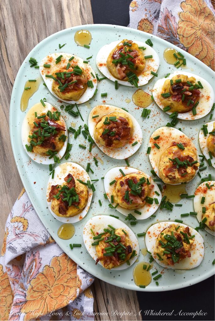 Bacon & Chive Deviled Eggs with Hot Honey - Deviled eggs are a classic crowd-pleaser and perfect for warm weather. If you're thinking about hosting a summer picnic or gathering, you definitely need to include some of these bacon-filled deviled eggs on the menu. They're topped with paprika, fresh chives, and even more bacon for a delicious twist on the classic recipe. And for an extra kick of flavor, they're drizzled with sweet and spicy hot honey infused with chilies.