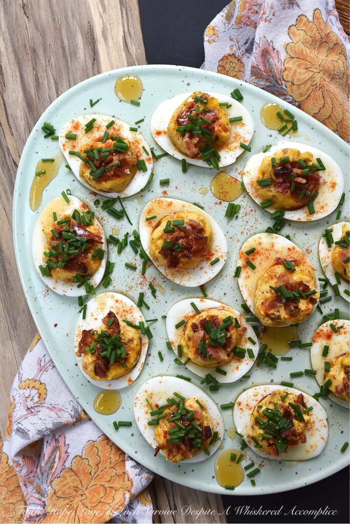 Bacon & Chive Deviled Eggs with Hot Honey - Deviled eggs are a classic crowd-pleaser and perfect for warm weather. If you're thinking about hosting a summer picnic or gathering, you definitely need to include some of these bacon-filled deviled eggs on the menu. They're topped with paprika, fresh chives, and even more bacon for a delicious twist on the classic recipe. And for an extra kick of flavor, they're drizzled with sweet and spicy hot honey infused with chilies.