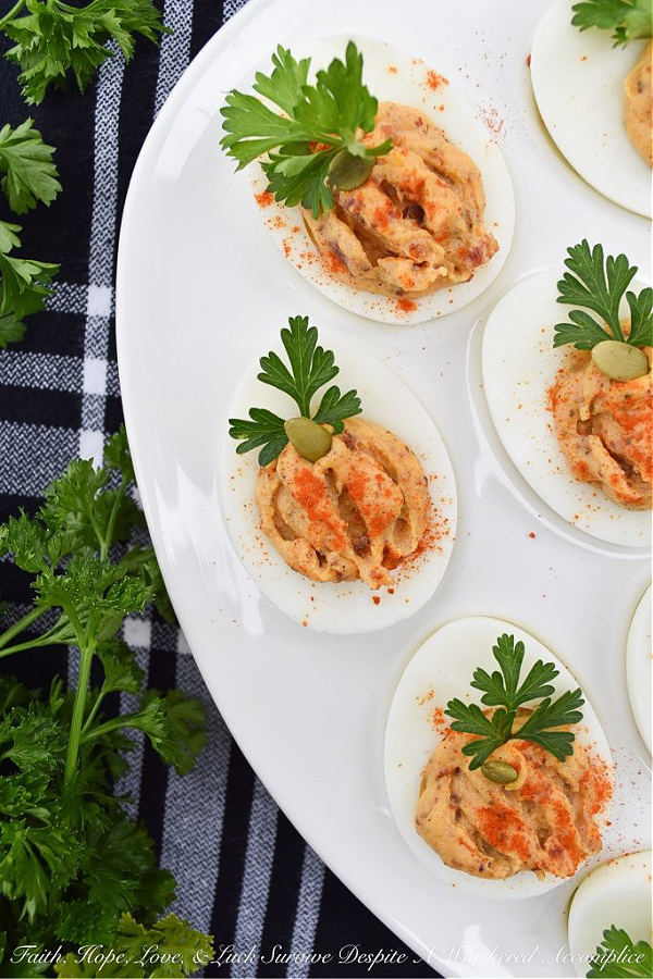 Bacon & Paprika Pumpkin Deviled Eggs - When you're searching for an autumn party deviled egg recipe that not only tastes amazing but looks festive, this is the recipe you need. Not only do crispy bacon and paprika add tons of flavor, as well as texture, but parsley leaves and roasted salted pumpkin seeds give these little pumpkin-shaped deviled eggs the perfect fall party appearance. They're the perfect excuse to throw a party.