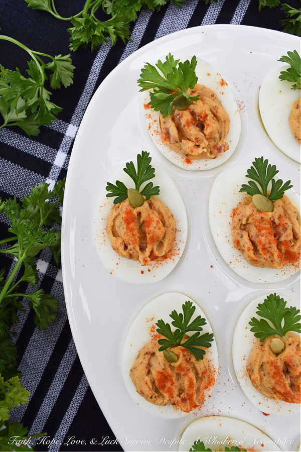 Bacon & Paprika Pumpkin Deviled Eggs - When you're searching for an autumn party deviled egg recipe that not only tastes amazing but looks festive, this is the recipe you need. Not only do crispy bacon and paprika add tons of flavor, as well as texture, but parsley leaves and roasted salted pumpkin seeds give these little pumpkin-shaped deviled eggs the perfect fall party appearance. They're the perfect excuse to throw a party.