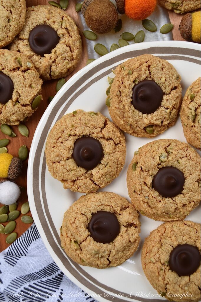 Flourless Pumpkin Seed Peanut Butter Blossoms - There's just something about the crisp air and changing leaves of fall that makes autumn the perfect season for baking. These peanut butter blossoms are a sinfully delicious combination of creamy peanut butter and dark chocolate Hershey's Kisses. And, for a delightful and unique fall twist, crushed pumpkin seeds are added to the cookie dough, to give these 6-ingredient cookies a little extra crunch as well as a touch of autumn flavor.