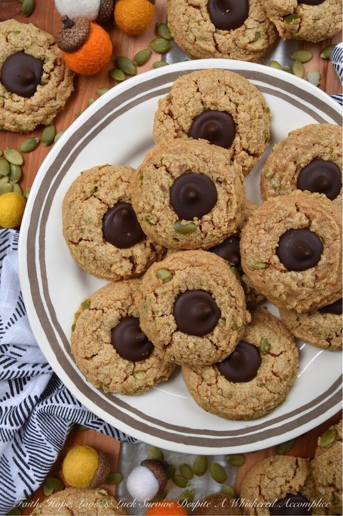 Flourless Pumpkin Seed Peanut Butter Blossoms - There's just something about the crisp air and changing leaves of fall that makes autumn the perfect season for baking. These peanut butter blossoms are a sinfully delicious combination of creamy peanut butter and dark chocolate Hershey's Kisses. And, for a delightful and unique fall twist, crushed pumpkin seeds are added to the cookie dough, to give these 6-ingredient cookies a little extra crunch as well as a touch of autumn flavor.