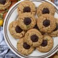 Flourless Pumpkin Seed Peanut Butter Blossoms - There's just something about the crisp air and changing leaves of fall that makes autumn the perfect season for baking. These peanut butter blossoms are a sinfully delicious combination of creamy peanut butter and dark chocolate Hershey's Kisses. And, for a delightful and unique fall twist, crushed pumpkin seeds are added to the cookie dough, to give these 6-ingredient cookies a little extra crunch as well as a touch of autumn flavor.