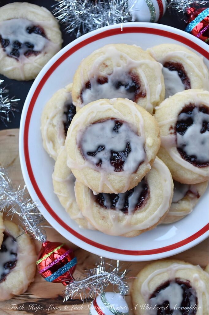 Raspberry-Cranberry Thumbprint Shortbread Cookies - These festive raspberry and cranberry thumbprint cookies, topped with a simple powdered sugar vanilla glaze, are a delicious treat that combines buttery, sweet, and fruity flavors to make them utterly irresistible. And, with the ability to use any brand or variety of mixed berry jam, jelly, or preserves, you can create an array of different flavors for your cookie tray or platter. Whether you bake these cookies for a special occasion or just because you're craving something sweet, they're sure to be a hit.