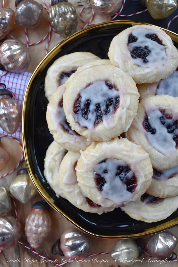 Orange Mixed Berry Glazed Thumbprint Cookies - These gorgeous mixed berry preserves-filled orange thumbprint cookies, topped with a simple orange and vanilla extract powdered glaze, are a delicious treat that combines buttery, sweet, citrusy, and fruity flavors to create a cookie worthy of any cookie tray or platter. Whether you bake these cookies during the holidays or just because you’re craving something sweet, they're guaranteed to be an instant hit with anyone who tries them.
