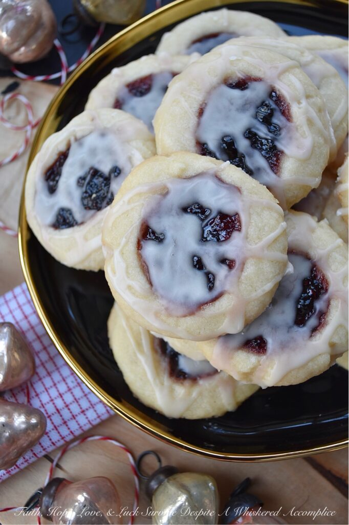 Orange Mixed Berry Glazed Thumbprint Cookies - These gorgeous mixed berry preserves-filled orange thumbprint cookies, topped with a simple orange and vanilla extract powdered glaze, are a delicious treat that combines buttery, sweet, citrusy, and fruity flavors to create a cookie worthy of any cookie tray or platter. Whether you bake these cookies during the holidays or just because you’re craving something sweet, they're guaranteed to be an instant hit with anyone who tries them.