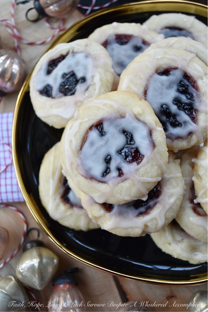 Orange Mixed Berry Glazed Thumbprint Cookies - These gorgeous mixed berry preserves-filled orange thumbprint cookies, topped with a simple orange and vanilla extract powdered glaze, are a delicious treat that combines buttery, sweet, citrusy, and fruity flavors to create a cookie worthy of any cookie tray or platter. Whether you bake these cookies during the holidays or just because you’re craving something sweet, they're guaranteed to be an instant hit with anyone who tries them.