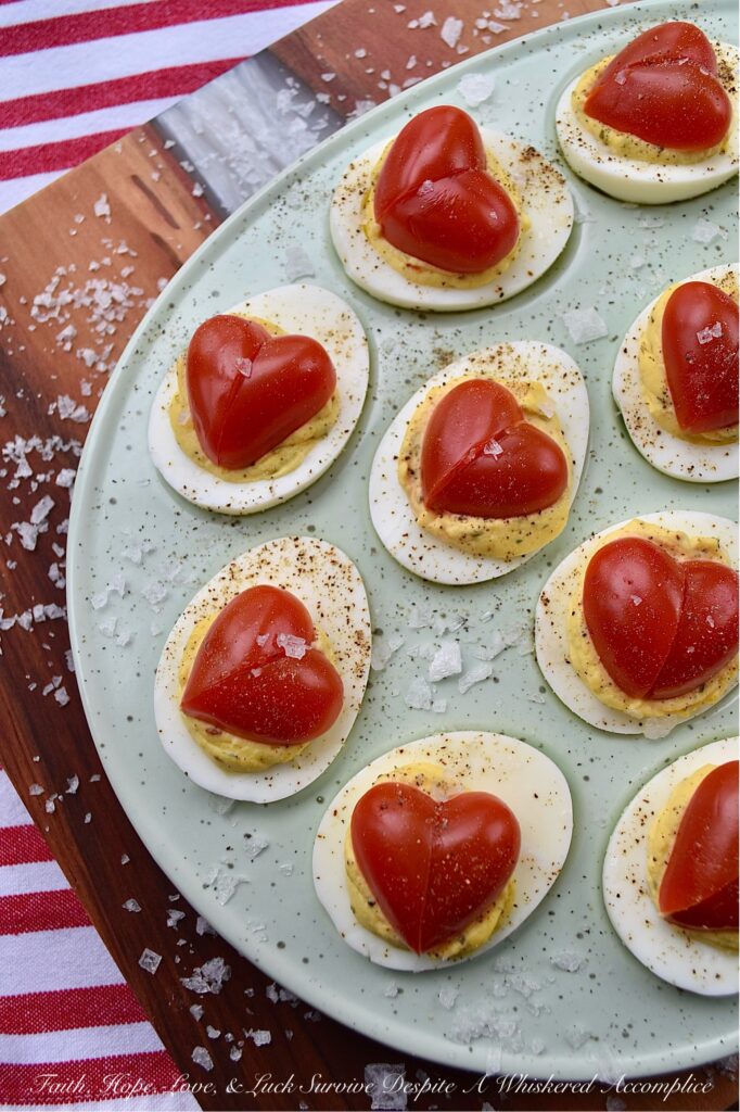 Italian Deviled Eggs with Heart-Shaped Tomatoes - These creamy Italian-seasoned deviled eggs are perfect for weddings, anniversary parties, Galentine's celebrations, Valentine's Day, or as a way to show your loved ones just how much you love them. Topped with a heart-shaped tomato for an added festive touch, these deviled eggs are as gorgeous and whimsical as they are delicious. Their slightly sweet honey and Italian seasoning filling will have everyone falling in love at first bite.