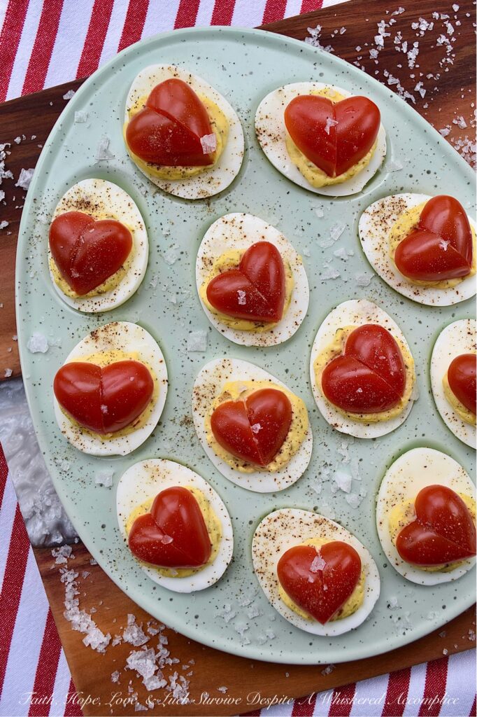 Italian Deviled Eggs with Heart-Shaped Tomatoes - These creamy Italian-seasoned deviled eggs are perfect for weddings, anniversary parties, Galentine's celebrations, Valentine's Day, or as a way to show your loved ones just how much you love them. Topped with a heart-shaped tomato for an added festive touch, these deviled eggs are as gorgeous and whimsical as they are delicious. Their slightly sweet honey and Italian seasoning filling will have everyone falling in love at first bite.