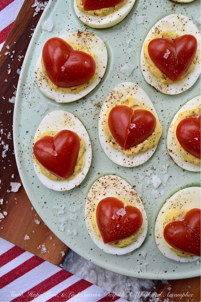 Italian Deviled Eggs with Heart-Shaped Tomatoes - These creamy Italian-seasoned deviled eggs are perfect for weddings, anniversary parties, Galentine's celebrations, Valentine's Day, or as a way to show your loved ones just how much you love them. Topped with a heart-shaped tomato for an added festive touch, these deviled eggs are as gorgeous and whimsical as they are delicious. Their slightly sweet honey and Italian seasoning filling will have everyone falling in love at first bite.