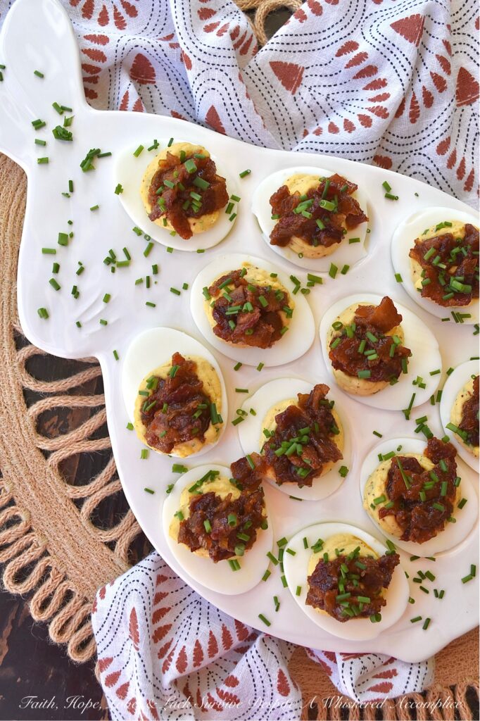 Deviled Eggs with Bourbon & Onion Bacon Jam - Get ready to wow your friends and family with this irresistible deviled egg recipe that is anything but traditional. By adding a sweet, salty, smoky, tangy, and slightly boozy bourbon and onion bacon jam, you can take your deviled eggs to the next level. The combination of rich, salty bacon, sweet yellow onions, smoky chili powder, and a touch of maple syrup and brown sugar creates an over-the-top flavor profile that is sure to impress. And with the addition of onion powder and chives to the egg filling, these deviled eggs are anything but boring with their oniony flavor.