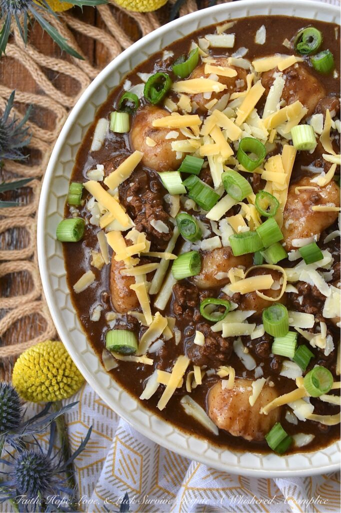 Guinness Stew Cincinnati Chili with Gnocchi - This hearty and flavorful one-pot stew and chili mash-up combines the bold flavors of Guinness stew and Cincinnati chili while taking things to the next level with the addition of potato gnocchi and a garnish of freshly shredded cheddar cheese and finely chopped scallions. Packed with spices and a perfect balance of sweetness and heat, this dish is sure to become a new favorite. And, since the gnocchi get even more soft and pillowy as the Guinness Stew Cincinnati Chili with Gnocchi rests overnight in the fridge, this is the perfect meal to make ahead and serve on a busy weeknight.