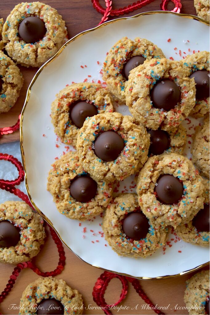 Firecracker Oatmeal Peanut Butter Blossoms - With their combination of creamy peanut butter and chocolatey Hershey's Kisses, these patriotic oatmeal peanut butter blossoms will almost surely cause a summer flavor explosion. These delightful blossom cookies are adorned with a festive and vibrant firecracker-inspired sprinkle of decorative red, white, and blue sugar, making them the perfect addition to any mid-summer celebration or 4th of July gathering.