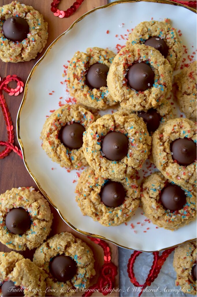 Firecracker Oatmeal Peanut Butter Blossoms - With their combination of creamy peanut butter and chocolatey Hershey's Kisses, these patriotic oatmeal peanut butter blossoms will almost surely cause a summer flavor explosion. These delightful blossom cookies are adorned with a festive and vibrant firecracker-inspired sprinkle of decorative red, white, and blue sugar, making them the perfect addition to any mid-summer celebration or 4th of July gathering.