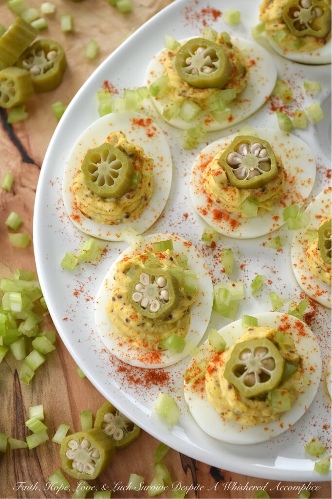 Cajun Deviled Eggs Garnished with Pickled Okra - These Cajun deviled eggs are anything but ordinary. Imagine a creamy, tangy deviled egg filling, kicked up a notch with the vibrant flavors of Cajun seasoning, whole-grain mustard, black pepper, and just a hint of onion powder. These little bites of heaven are then topped with a sprinkle of paprika, a touch of finely chopped celery, and a tangy slice of pickled okra for the ultimate Southern flair. Whether you're celebrating Mardi Gras or simply craving a bold and flavorful bite, these Cajun deviled eggs are sure to be a crowd-pleaser.