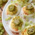 Cajun Deviled Eggs Garnished with Pickled Okra - These Cajun deviled eggs are anything but ordinary. Imagine a creamy, tangy deviled egg filling, kicked up a notch with the vibrant flavors of Cajun seasoning, whole-grain mustard, black pepper, and just a hint of onion powder. These little bites of heaven are then topped with a sprinkle of paprika, a touch of finely chopped celery, and a tangy slice of pickled okra for the ultimate Southern flair. Whether you're celebrating Mardi Gras or simply craving a bold and flavorful bite, these Cajun deviled eggs are sure to be a crowd-pleaser.