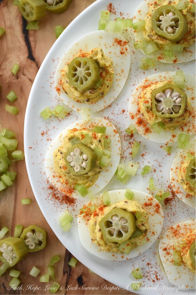 Cajun Deviled Eggs Garnished with Pickled Okra - These Cajun deviled eggs are anything but ordinary. Imagine a creamy, tangy deviled egg filling, kicked up a notch with the vibrant flavors of Cajun seasoning, whole-grain mustard, black pepper, and just a hint of onion powder. These little bites of heaven are then topped with a sprinkle of paprika, a touch of finely chopped celery, and a tangy slice of pickled okra for the ultimate Southern flair. Whether you're celebrating Mardi Gras or simply craving a bold and flavorful bite, these Cajun deviled eggs are sure to be a crowd-pleaser.