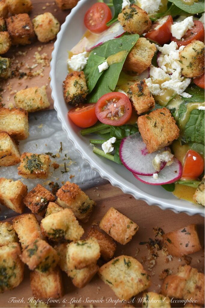Baked Homemade Buttery Herb Croutons - Tired of the same old salads? These incredibly delicious, homemade baked croutons are buttery and flavorful while adding the perfect crunch to almost any salad. After being cubed and tossed with an herb-infused savory butter mixture, white sandwich bread is baked to golden brown crunchy toasted crouton perfection. With these irresistible homemade croutons, you'll discover there's no such thing as a boring salad.