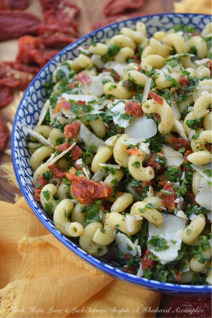 Sun-Dried Tomato & Kale Italian Pasta Salad - Don't let the kale in this homemade pasta salad scare you off. Its subtle, earthy flavor blends seamlessly into the salad while adding a pop of vibrant green color and a nutritional boost, which, in this simple salad, transforms the often-overlooked and disliked leafy green into a surprisingly delicious star ingredient. This vibrant and flavorful side dish features perfectly cooked spiral pasta tossed in a zesty Italian herb dressing, along with the addition of nutty parmesan cheese and the intense sweet flavor of sun-dried tomatoes. It's a guaranteed healthy crowd-pleaser, perfect for potlucks, picnics, or even as a weeknight meal.