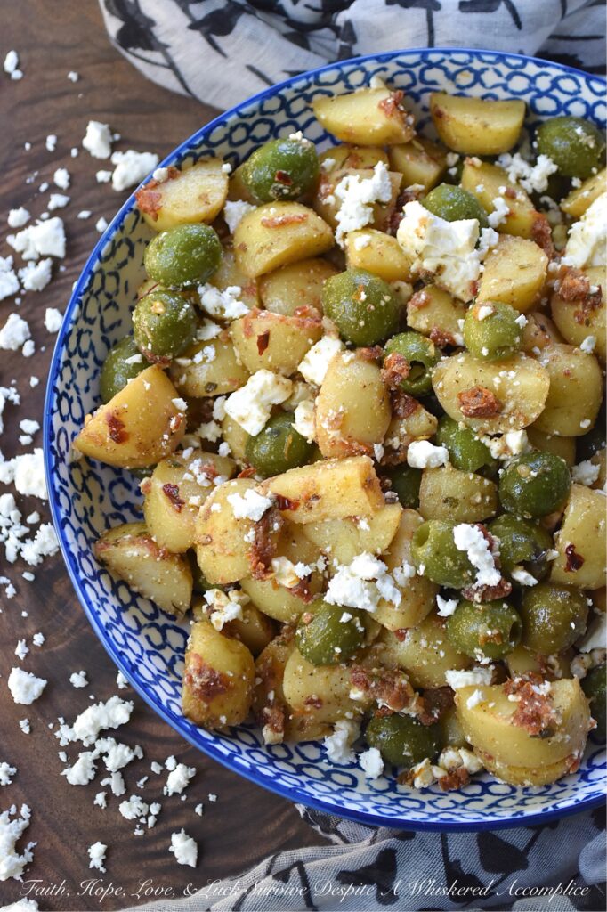 Green Olive & Sun Dried Tomato Potato Salad - Mayonnaise-based potato salads don't always fare well in the sweltering heat of a humid afternoon, so this summer, we’re ditching the mayo in favor of something much brighter, bolder, and infinitely more delicious. This Italian-inspired potato salad with whole pitted green olives and feta cheese is easy to make, holds up perfectly at a barbecue or picnic, and packs a rather serious flavor punch. By infusing olive oil with sun-dried tomatoes, dried herbs, and seasonings, this dressing transforms tender, boiled baby yellow potatoes into a side dish that will have everyone reaching for seconds.