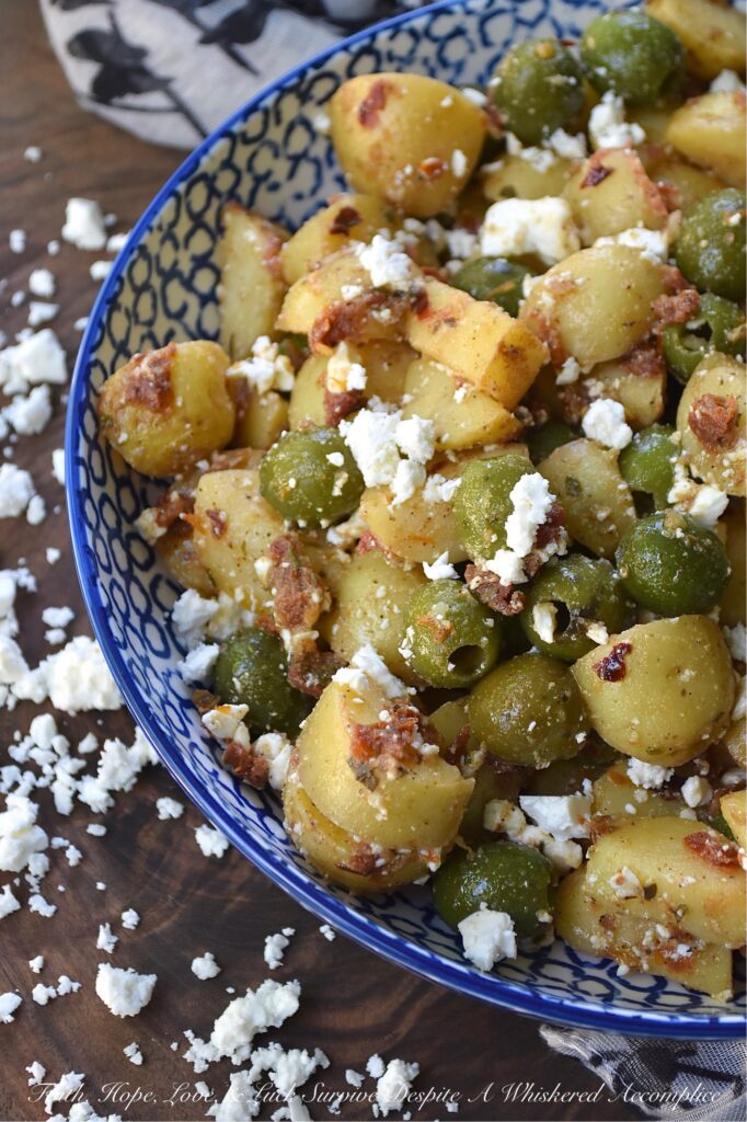 Green Olive & Sun Dried Tomato Potato Salad - Mayonnaise-based potato salads don't always fare well in the sweltering heat of a humid afternoon, so this summer, we’re ditching the mayo in favor of something much brighter, bolder, and infinitely more delicious. This Italian-inspired potato salad with whole pitted green olives and feta cheese is easy to make, holds up perfectly at a barbecue or picnic, and packs a rather serious flavor punch. By infusing olive oil with sun-dried tomatoes, dried herbs, and seasonings, this dressing transforms tender, boiled baby yellow potatoes into a side dish that will have everyone reaching for seconds.