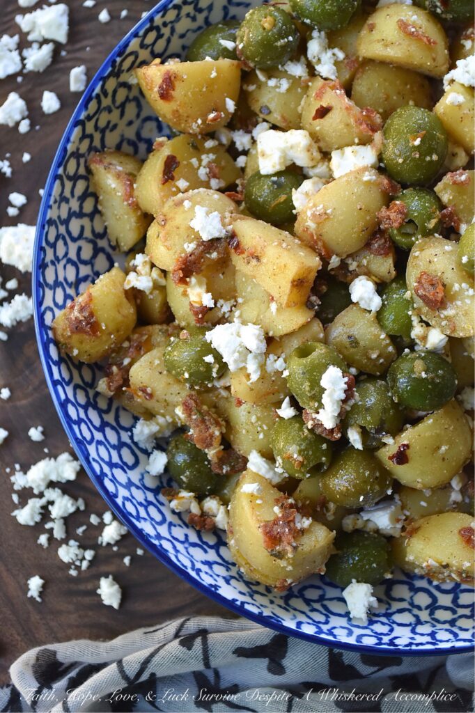 Green Olive & Sun Dried Tomato Potato Salad - Mayonnaise-based potato salads don't always fare well in the sweltering heat of a humid afternoon, so this summer, we’re ditching the mayo in favor of something much brighter, bolder, and infinitely more delicious. This Italian-inspired potato salad with whole pitted green olives and feta cheese is easy to make, holds up perfectly at a barbecue or picnic, and packs a rather serious flavor punch. By infusing olive oil with sun-dried tomatoes, dried herbs, and seasonings, this dressing transforms tender, boiled baby yellow potatoes into a side dish that will have everyone reaching for seconds.